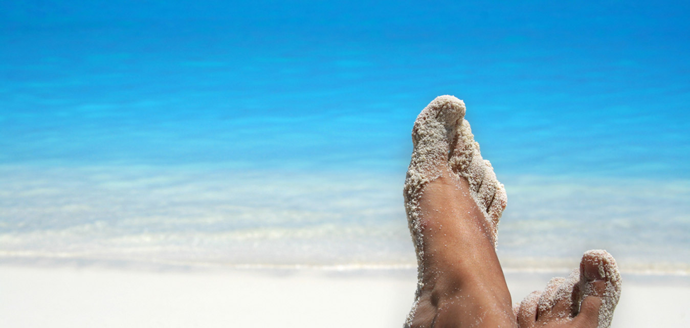 Sand covered feet relaxing in front of the Florida ocean.